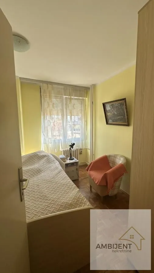 Smaller bedroom with a bed, an armchair, and a window.
