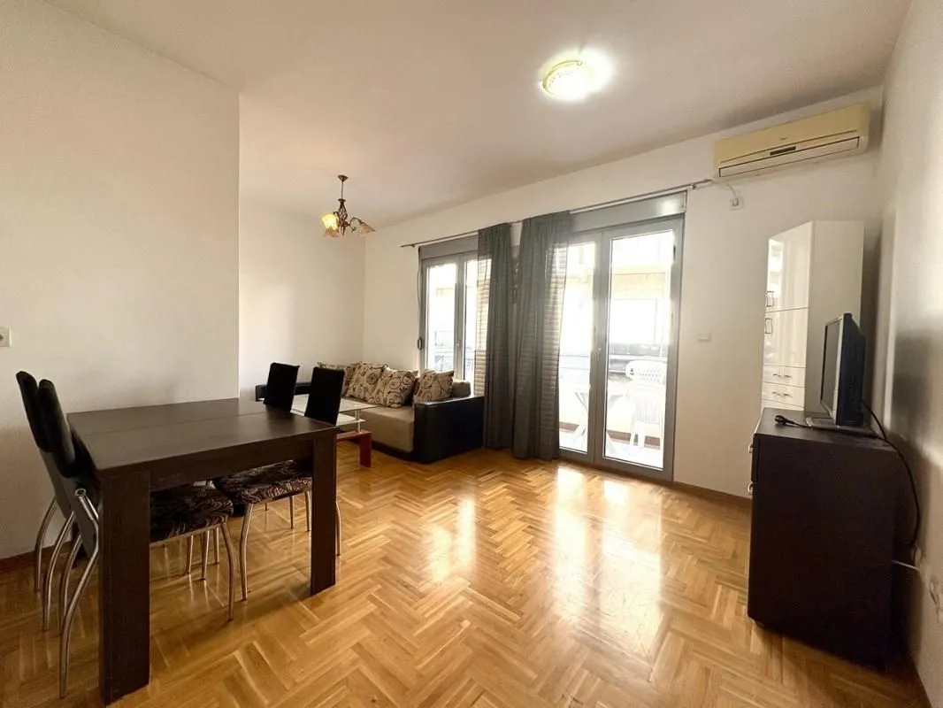 Living room with a dining area, parquet flooring, and access to the terrace.