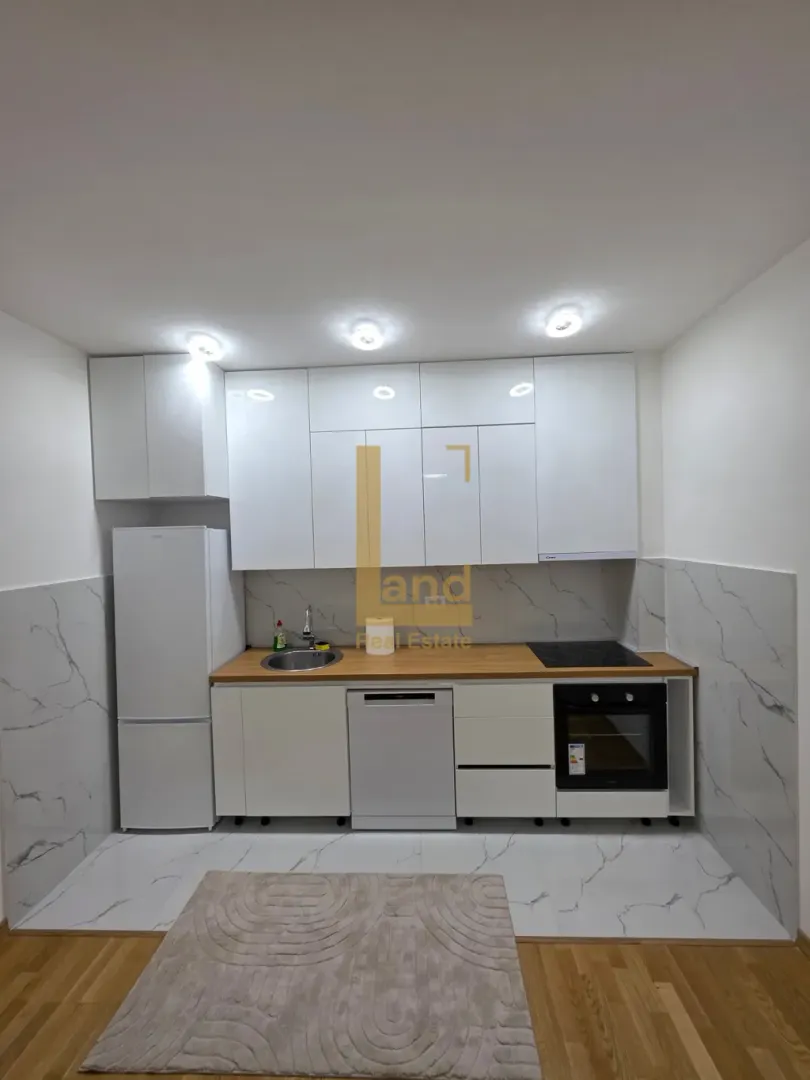 Modern white kitchen with built-in appliances and a wooden countertop.