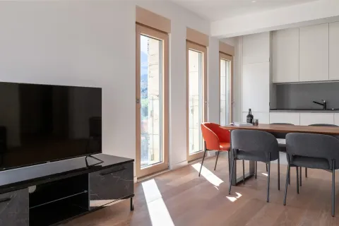 Living room with a TV, dining area and kitchen in the background. - image 8