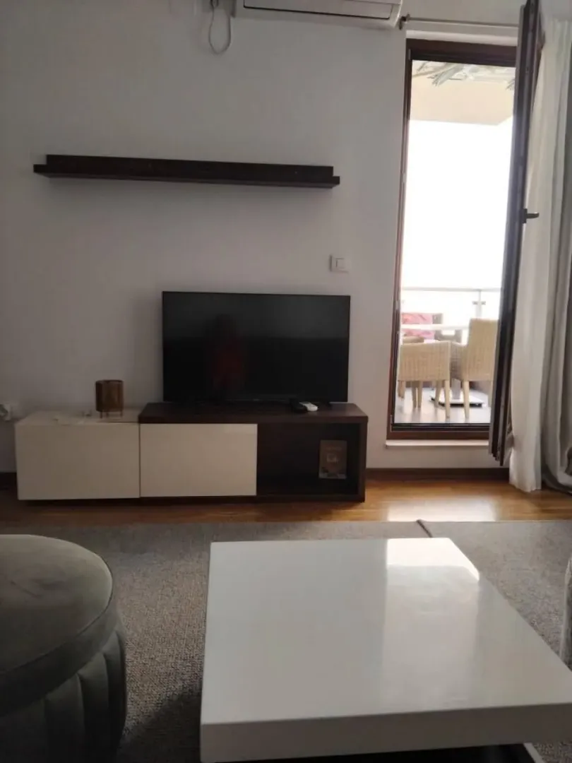 Dnevna soba sa televizorom i izlazom na terasu.