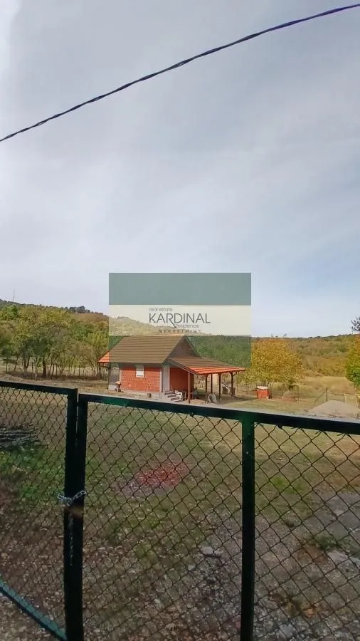 Pogled na manju kuću sa dvorištem iza ograde.