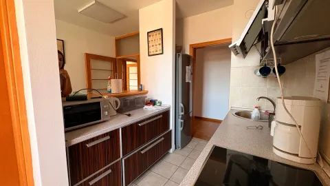 Small kitchen with wooden cabinets, appliances, and a view of the hallway. - image 7