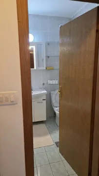 A simple bathroom with a sink and toilet, viewed through an open door. - image 4