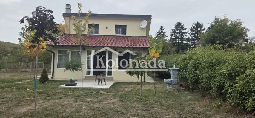 Pogled na dvorište i fasadu dvospratne kuće.