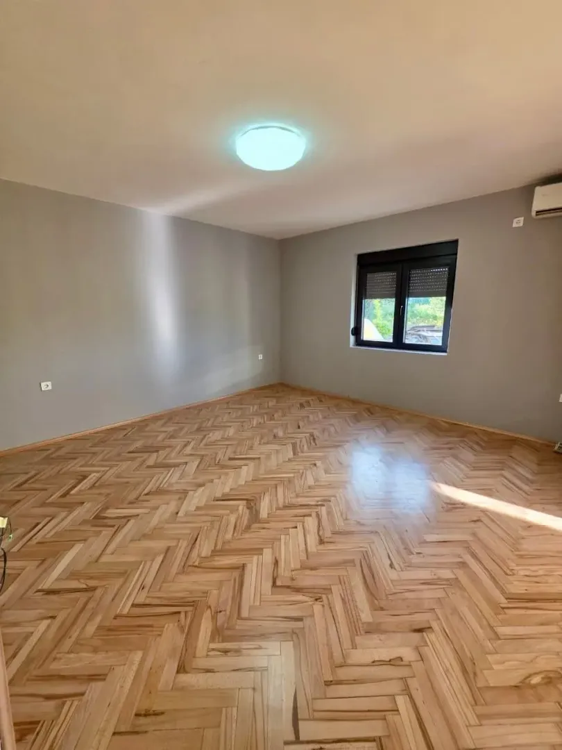 Empty room with wooden parquet flooring and grey walls.