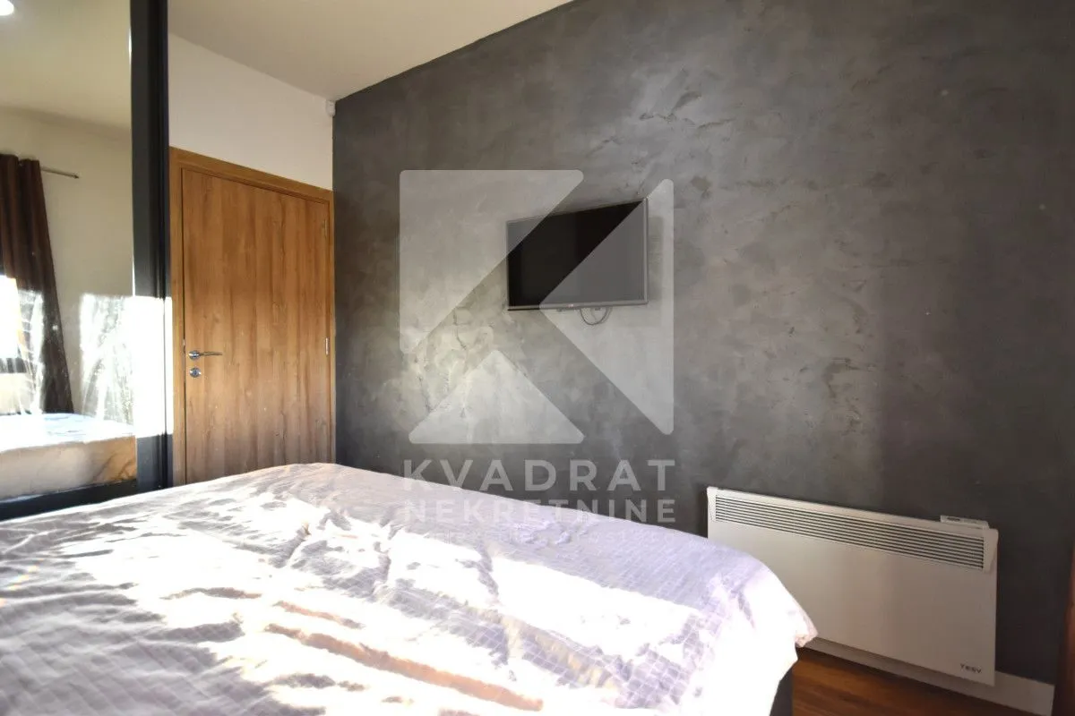 Bedroom with a double bed, grey wall, and a television.