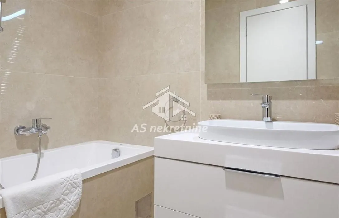 Modern bathroom equipped with a bathtub, washbasin, and mirror.