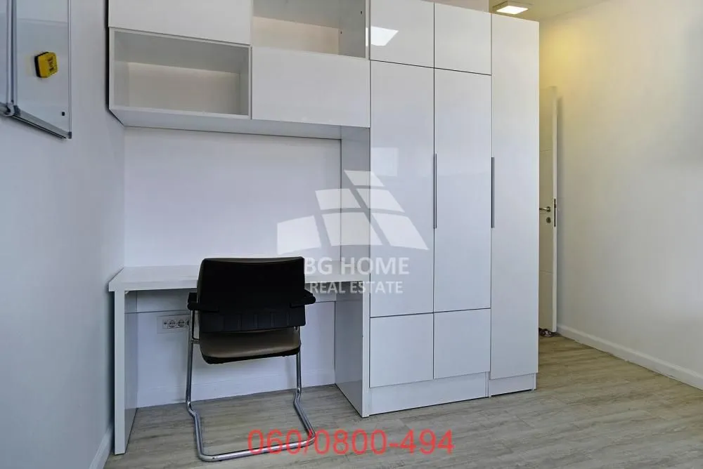 A desk with a white wardrobe and shelving in the room.