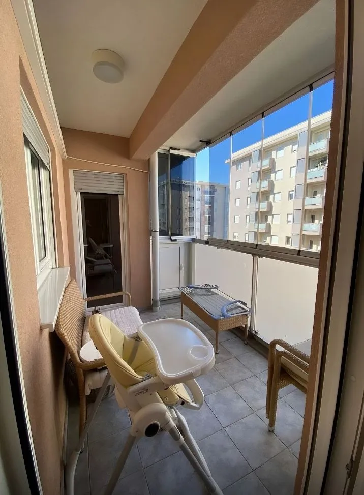 Covered balcony space with glass railings and furniture.