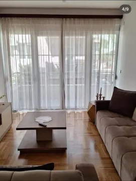 Living room with a sofa, coffee table, and large balcony doors. - image 3