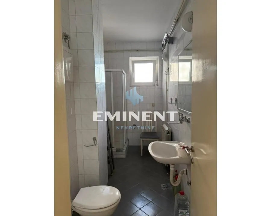 Smaller bathroom with a shower cabin, washbasin, and toilet.