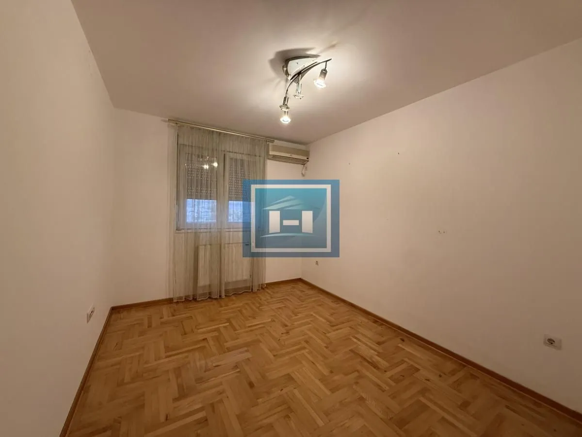 Empty room with hardwood floors and a window with curtains.