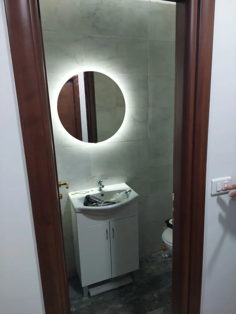 Pogled kroz vrata na kupatilo sa umivaonikom i ogledalom.