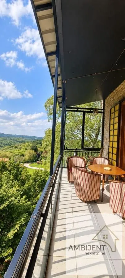 Natkrivena terasa sa garniturom za sedenje i pogledom na prirodu.