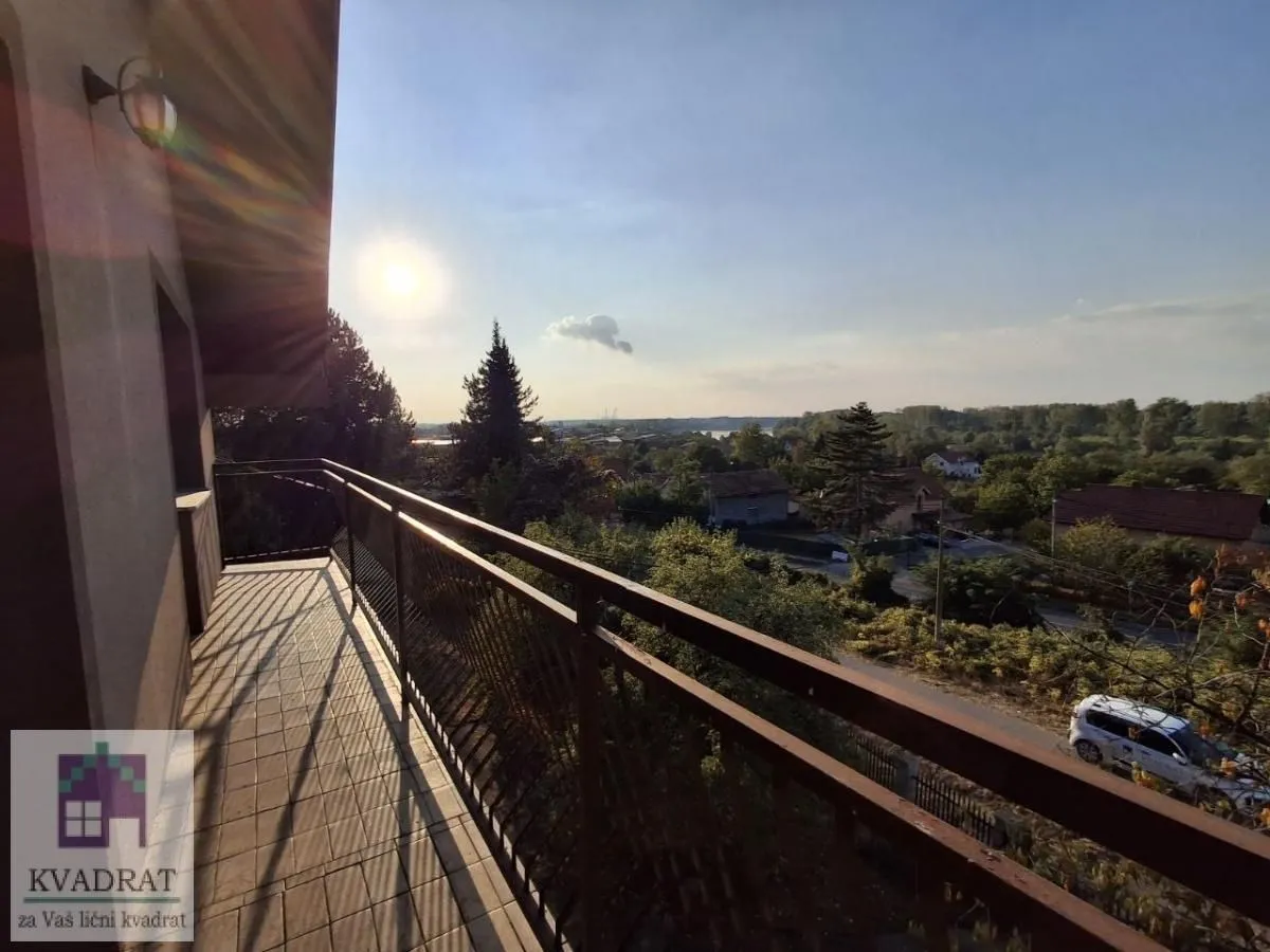 Natkriveni balkon sa metalnom ogradom i pogledom na okolinu.