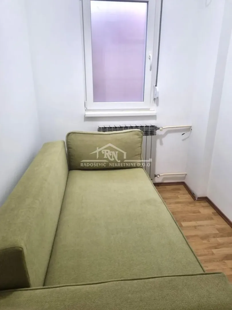 Small room with a green bed and a window.