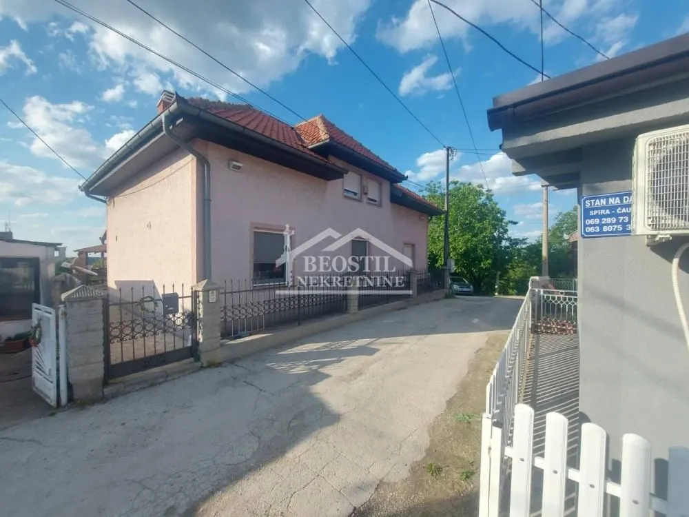Pogled na spoljašnjost kuće sa dvorištem i ogradom.