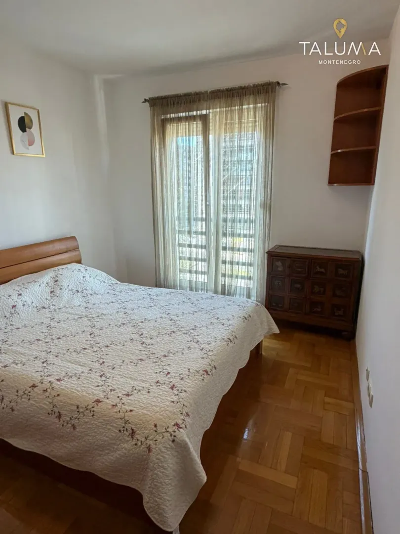 Bedroom with a double bed, wooden flooring, and balcony access.