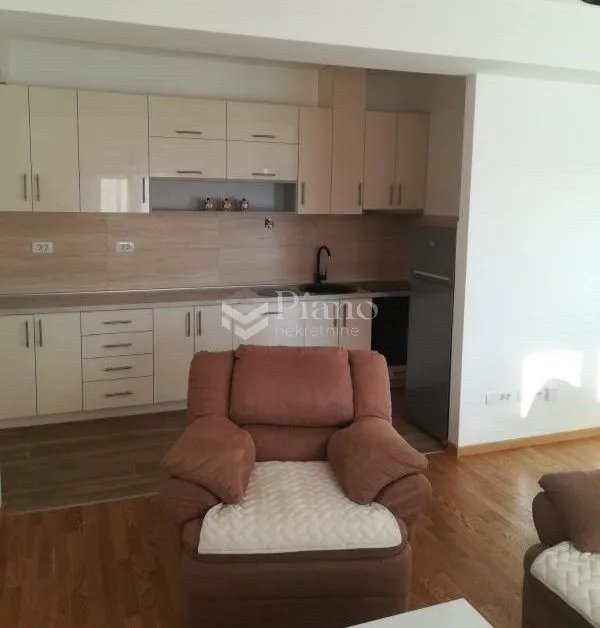 Open plan space featuring a kitchen and an armchair in the foreground.