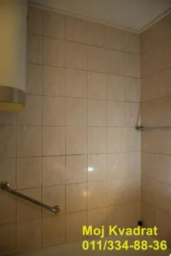 Pogled na popločani zid kupatila sa držačima. - image 10