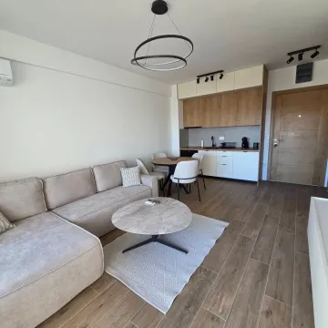 Living room with dining area and kitchen in bright tones. - image 2
