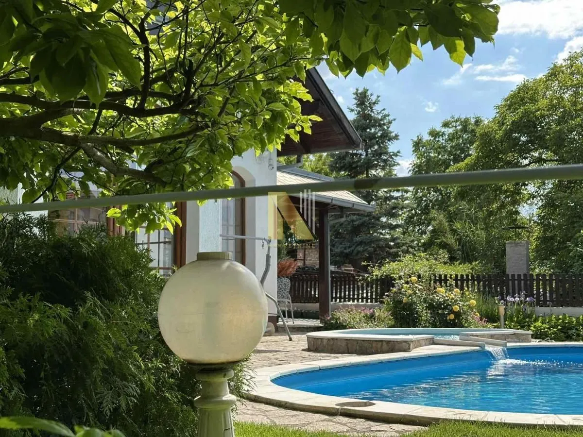Dvorište kuće sa bazenom i uređenom zelenom površinom.