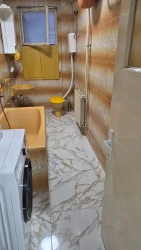 Bathroom with a bathtub, washbasin, toilet, and washing machine. - image 6