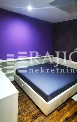 Bedroom with a double bed and a purple wall.