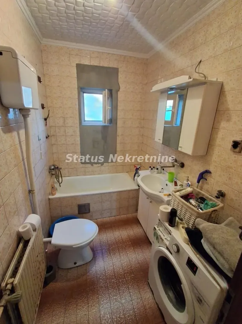 Manje kupatilo sa kadom, wc šoljom, umivaonikom i veš mašinom.