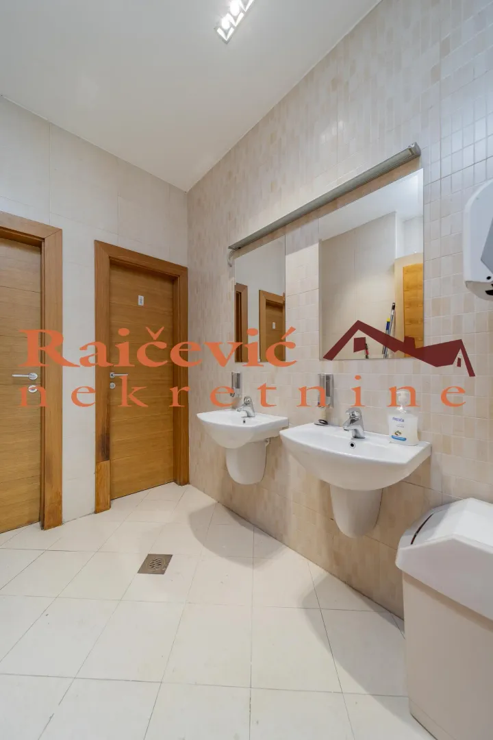 Public bathroom with two sinks, mirrors, and tiled walls.