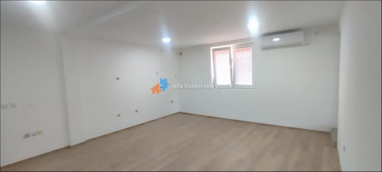 Empty room with white walls, laminate flooring, a window, and an air conditioner.