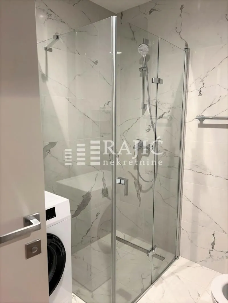 Modernly equipped bathroom with a shower cabin and marble tiles.