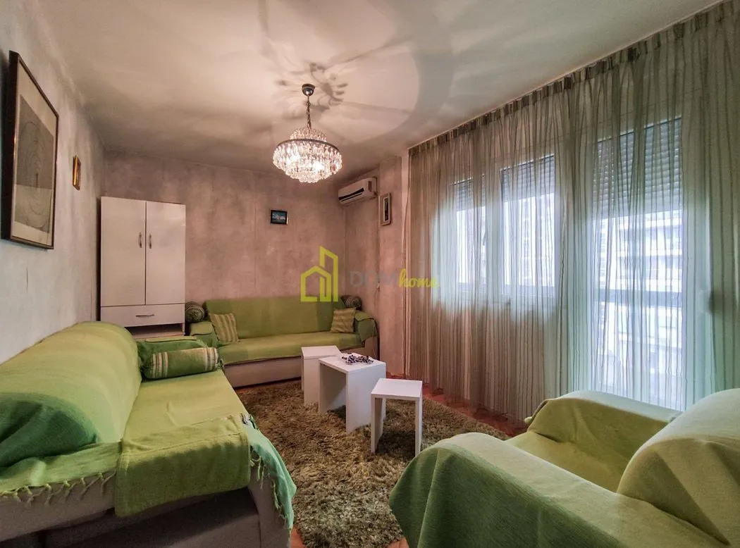 Dnevna soba sa garniturom za sedenje, stočićima i velikim prozorom.