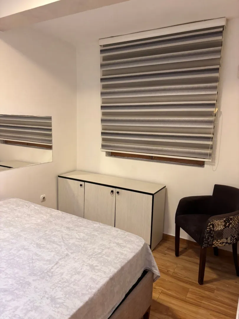 Smaller bedroom with a bed, dresser, and armchair.