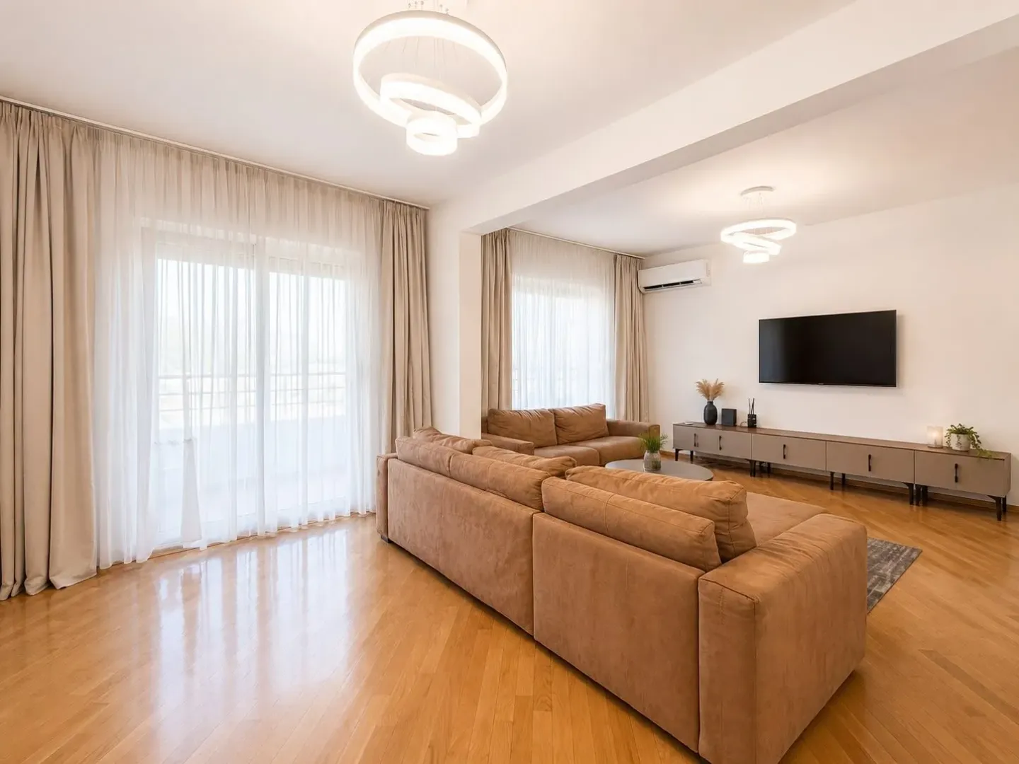 Spacious and bright living room with a sofa set and TV.