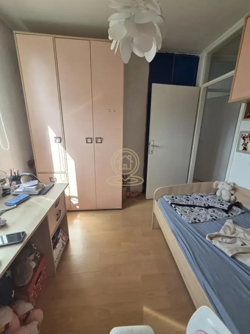 Children's bedroom with a bed, wardrobe, and desk.