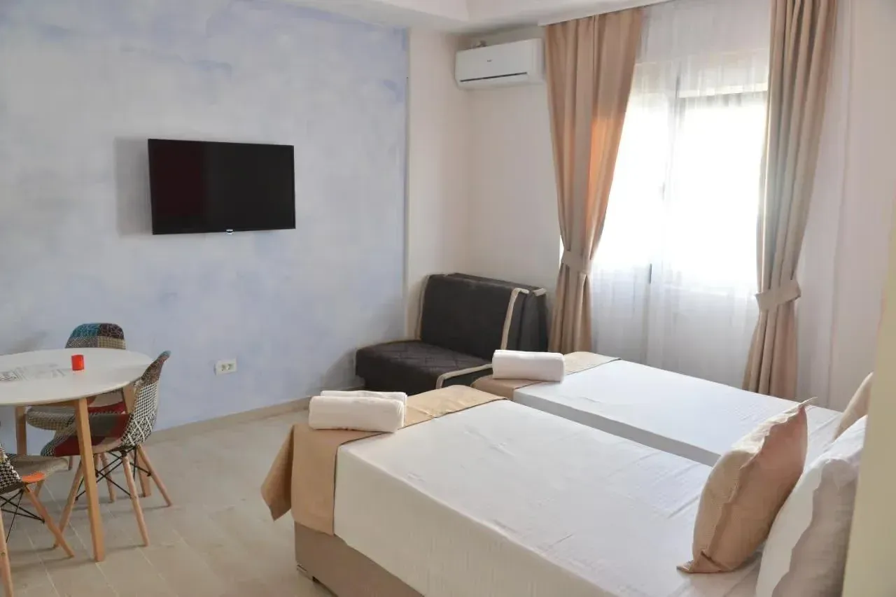 Bedroom with two single beds, a dining table, and an air conditioner.