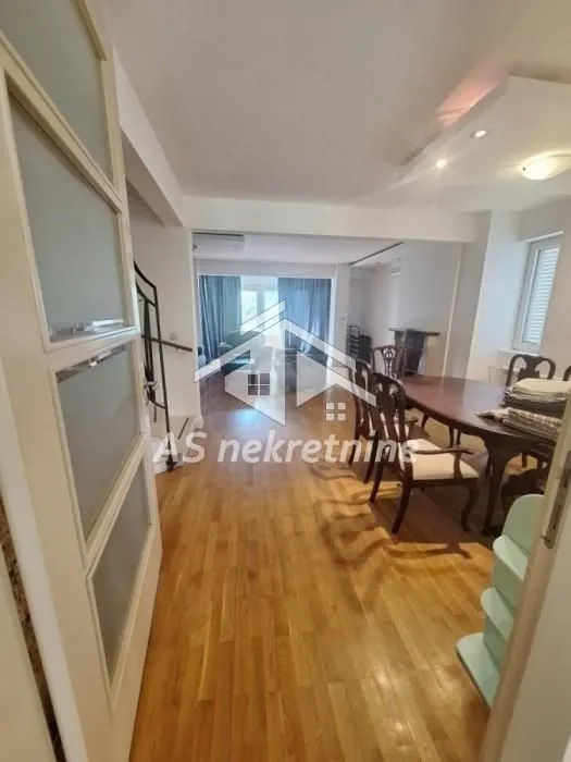Spacious living room with dining area and wooden flooring.