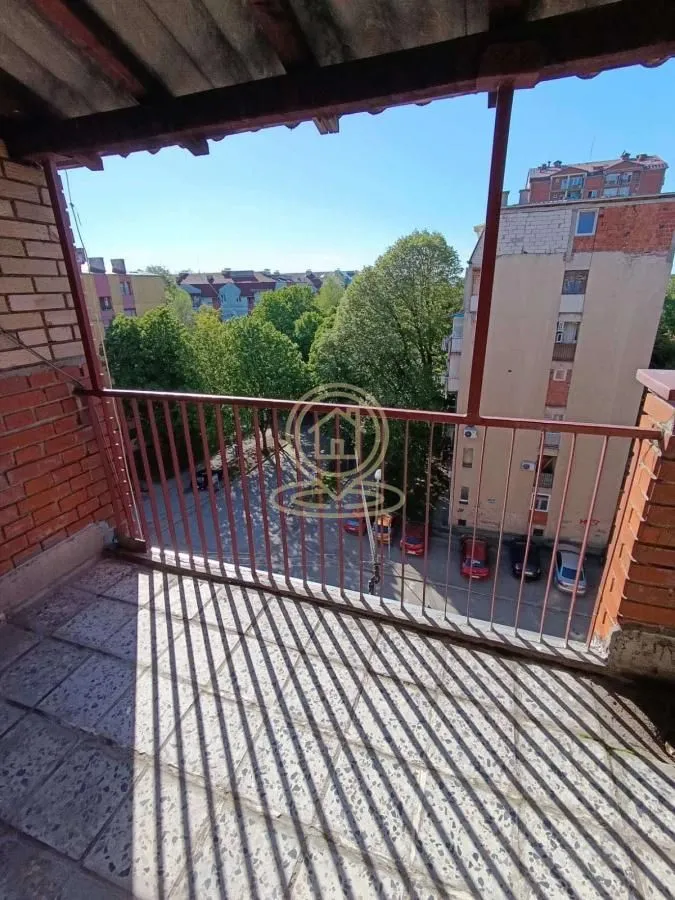 Natkriveni balkon sa pogledom na ulicu i zelene površine.