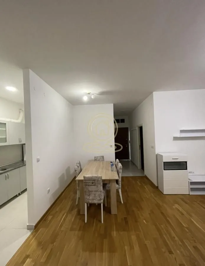 Trpezarija sa drvenim stolom i stolicama, povezana sa kuhinjom i hodnikom.