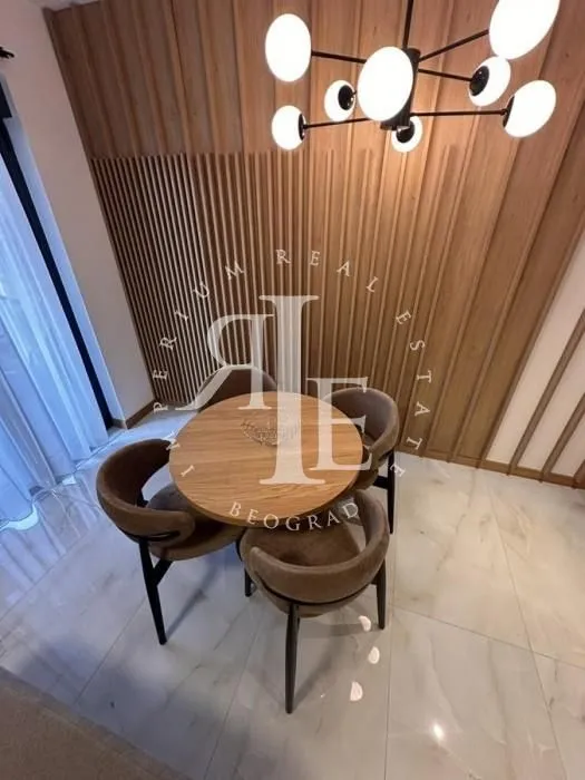 Trpezarijski sto sa četiri stolice i modernim lusterom.