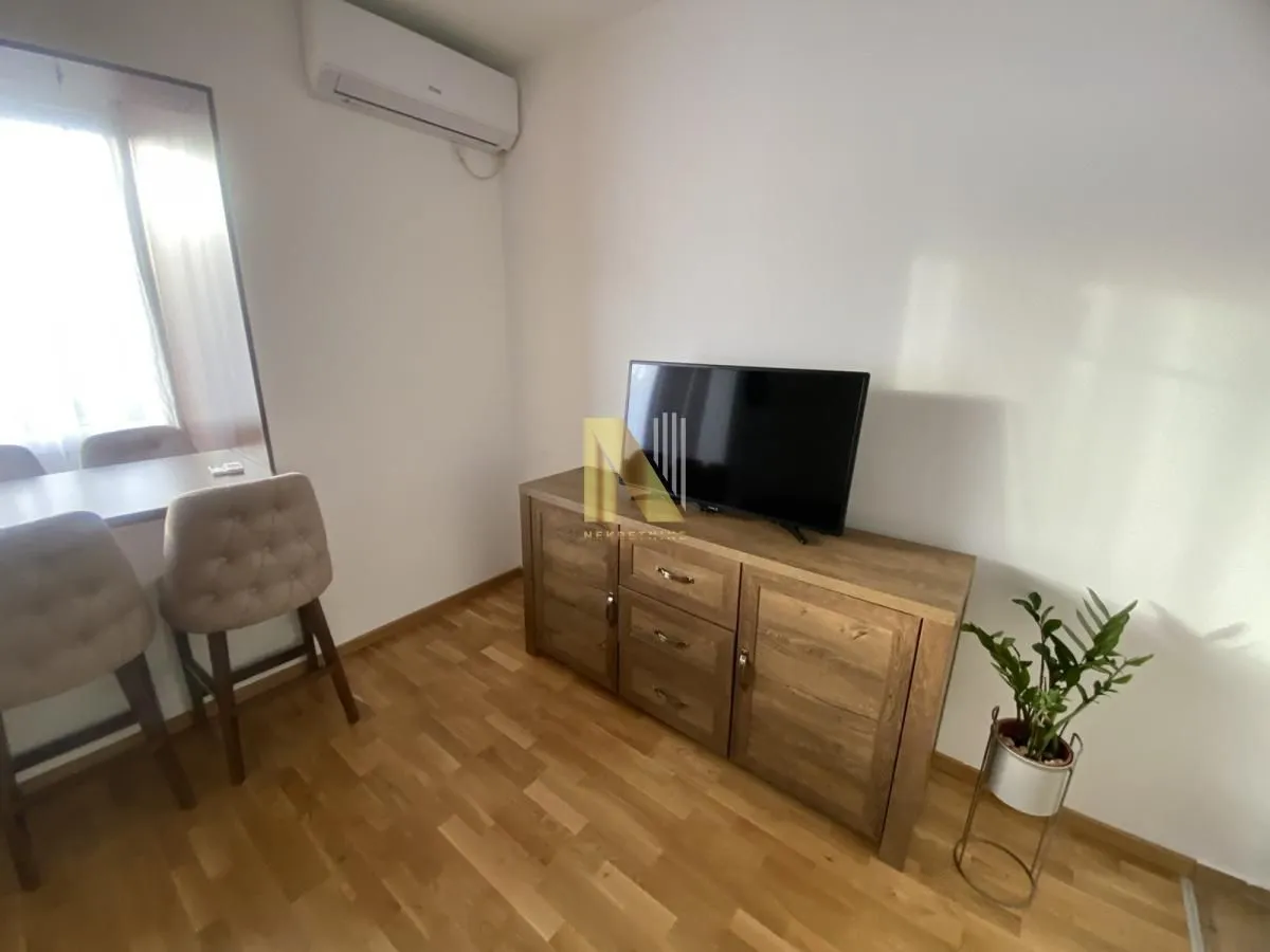 Living room with a wooden cabinet, television, and a dining table with chairs.