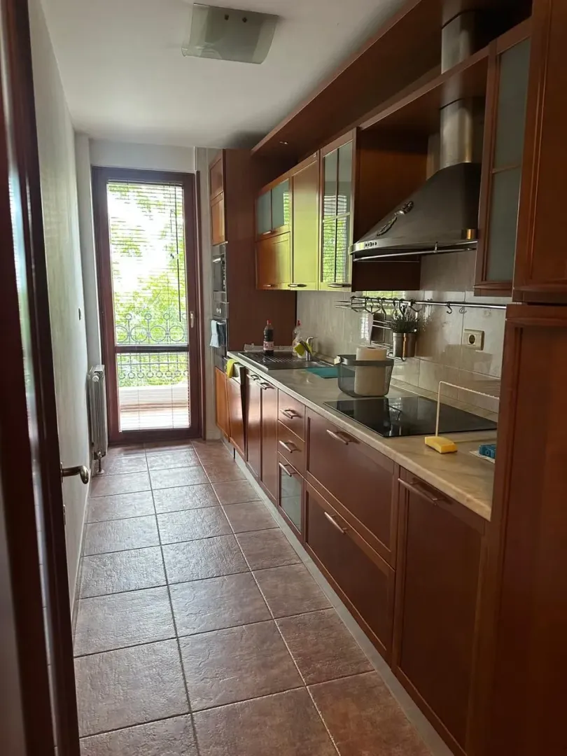 Narrow kitchen with wooden cabinets and access to the terrace.