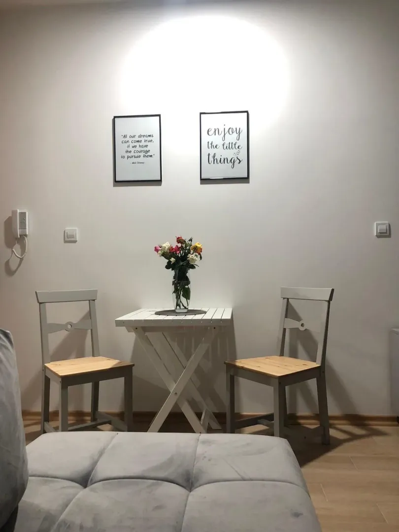Mali bijeli sto sa dvije stolice i ukrasnim slikama na zidu.
