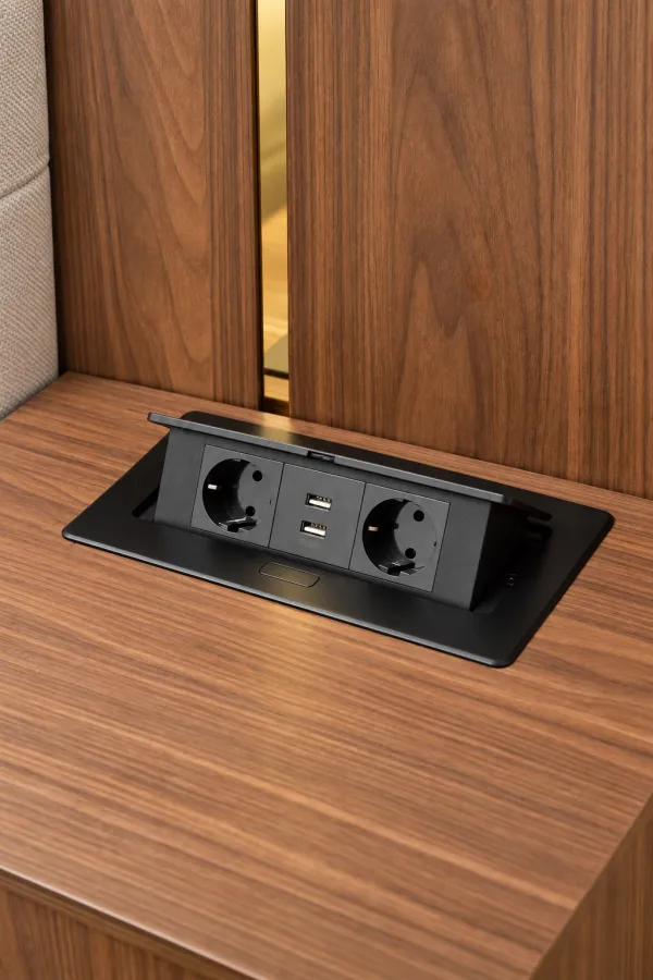 Krupni kadar ugradne utičnice sa USB priključcima na drvenoj površini.