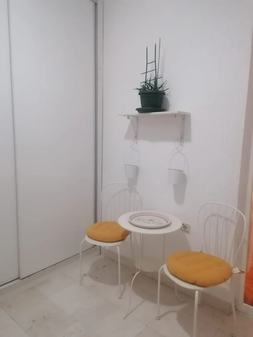 Manji zatvoreni prostor sa bijelim stocicem, dvije stolice i ugradnim plakarom.