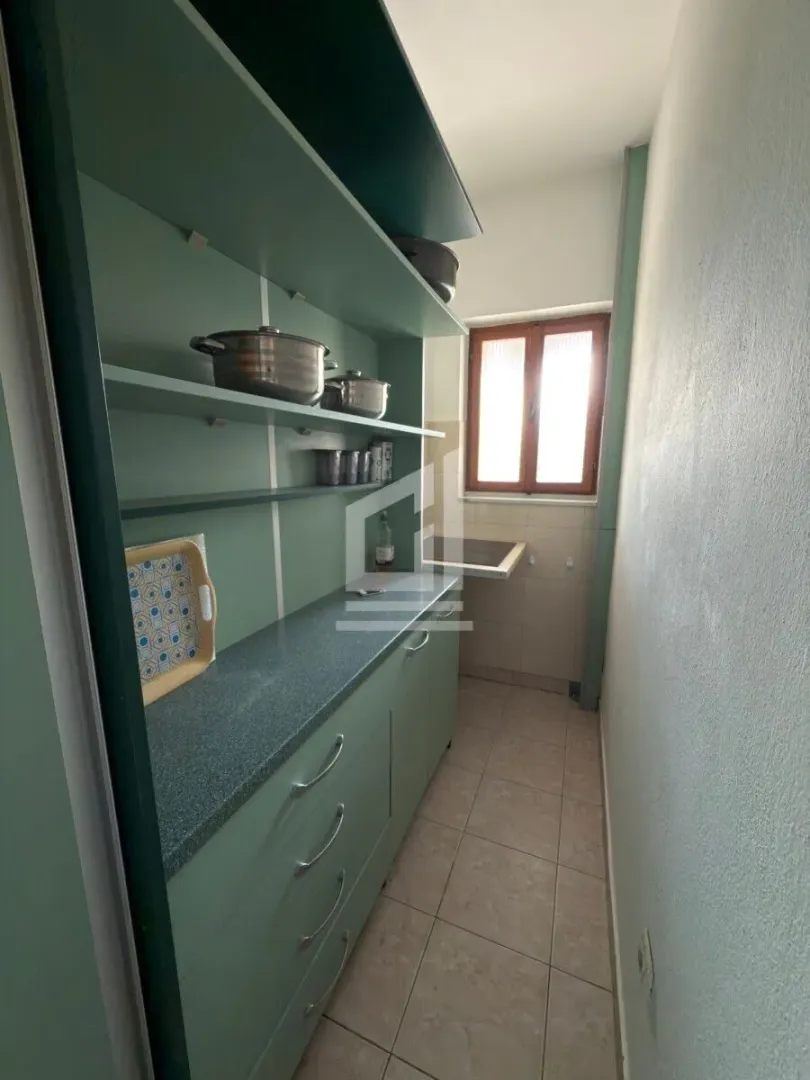 Smaller kitchen with green units and shelves.