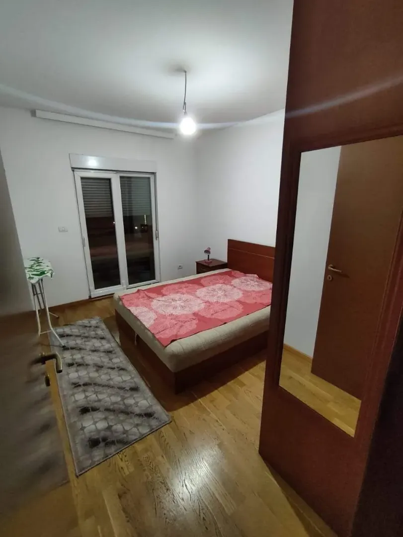 Jednostavno namještena spavaća soba sa bračnim krevetom i drvenim podovima.