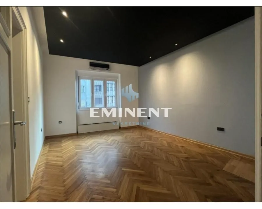 Empty room with parquet flooring and a black ceiling.